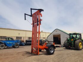 An OzValue Ag brand Bale Stacker, shown in a workyard in an upright position from a front right angle.